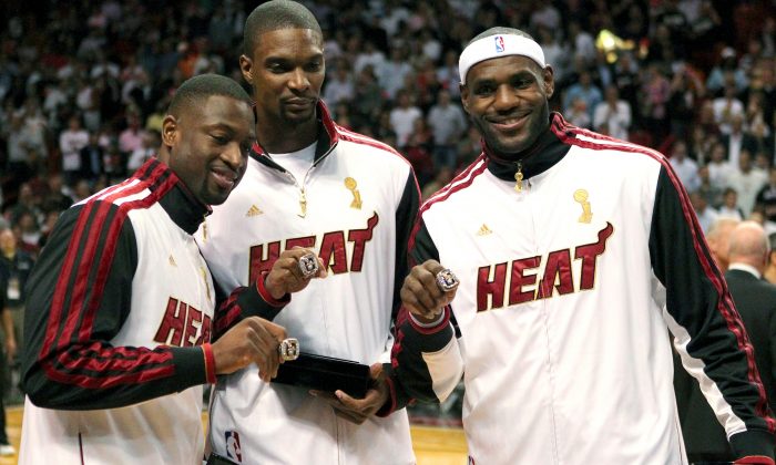 In this Oct. 30, 2012 file photo, Miami Heat's Dwyane Wade, left, Chris Bosh, center, and LeBron James pose with their championship rings during a ceremony before an NBA basketball game against the Boston Celtics in Miami. (AP Photo/El Nuevo Herald, David Santiago, File)