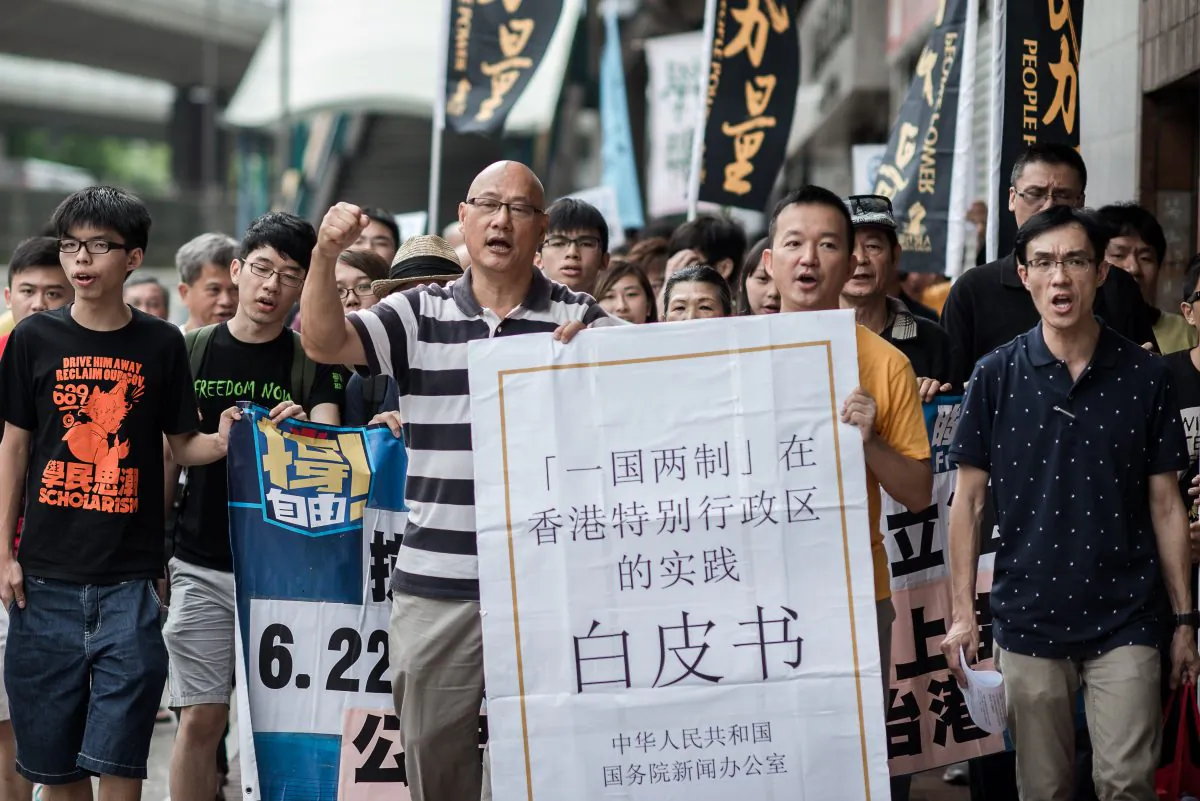 Demonstrators shout slogans, holding a large reproduction of Beijing's white paper, as they march toward Beijing's representative office in Hong Kong on June 11. China released a white paper document Tuesday emphasizing its control over Hong Kong. (Philippe Lopez/AFP/Getty Images) 