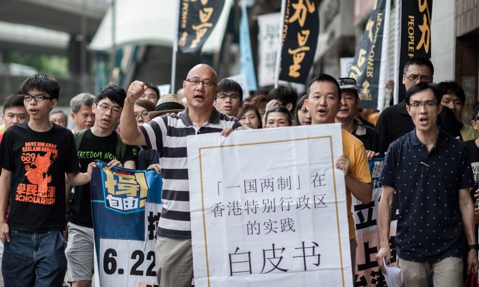 Demonstrators shout slogans, holding a large reproduction of Beijing's white paper, as they march toward Beijing's representative office in Hong Kong on June 11. China released a white paper document Tuesday emphasizing its control over Hong Kong. (Philippe Lopez/AFP/Getty Images) 