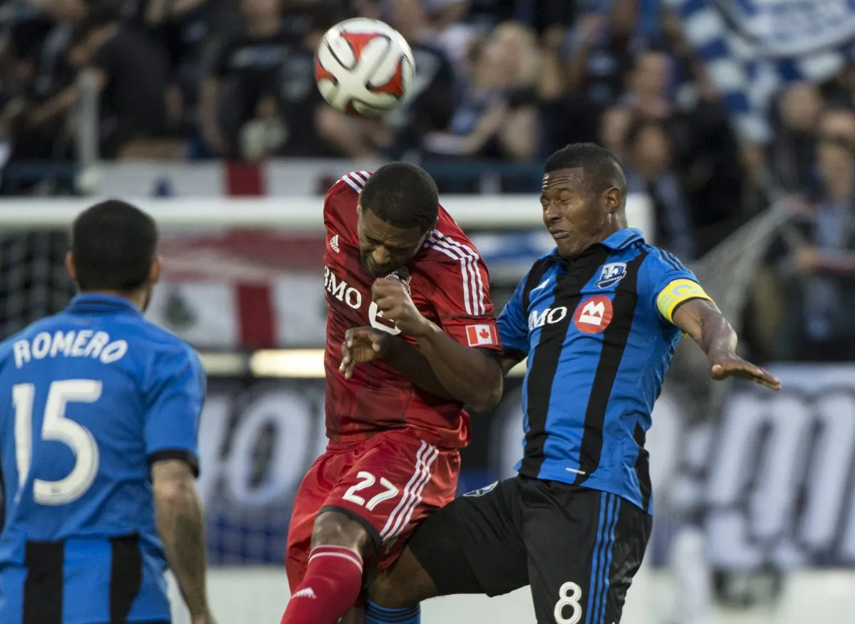 Toronto FC's Luke Moore heads the ball away from Montreal Impact's Patrice Bernier during first half Voyageurs Cup action on June 4, 2014 in Montreal.
(The Canadian Press/Paul Chiasson)