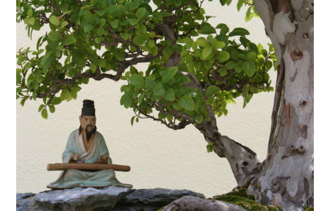 A small statue of an ancient Chinese musician playing the qin rests under a tree. The qin is a Chinese stringed instrument of the zither family. (Gabriel Eckert/Photos.com)