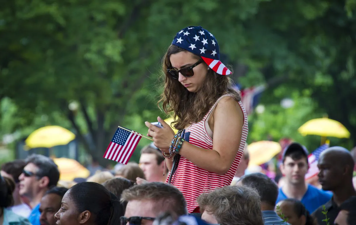 A girl checks her cellphone during the annual Independence Day Parade in Washington, D.C., July 04, 2013. (Mladen Antonov/AFP/Getty Images)