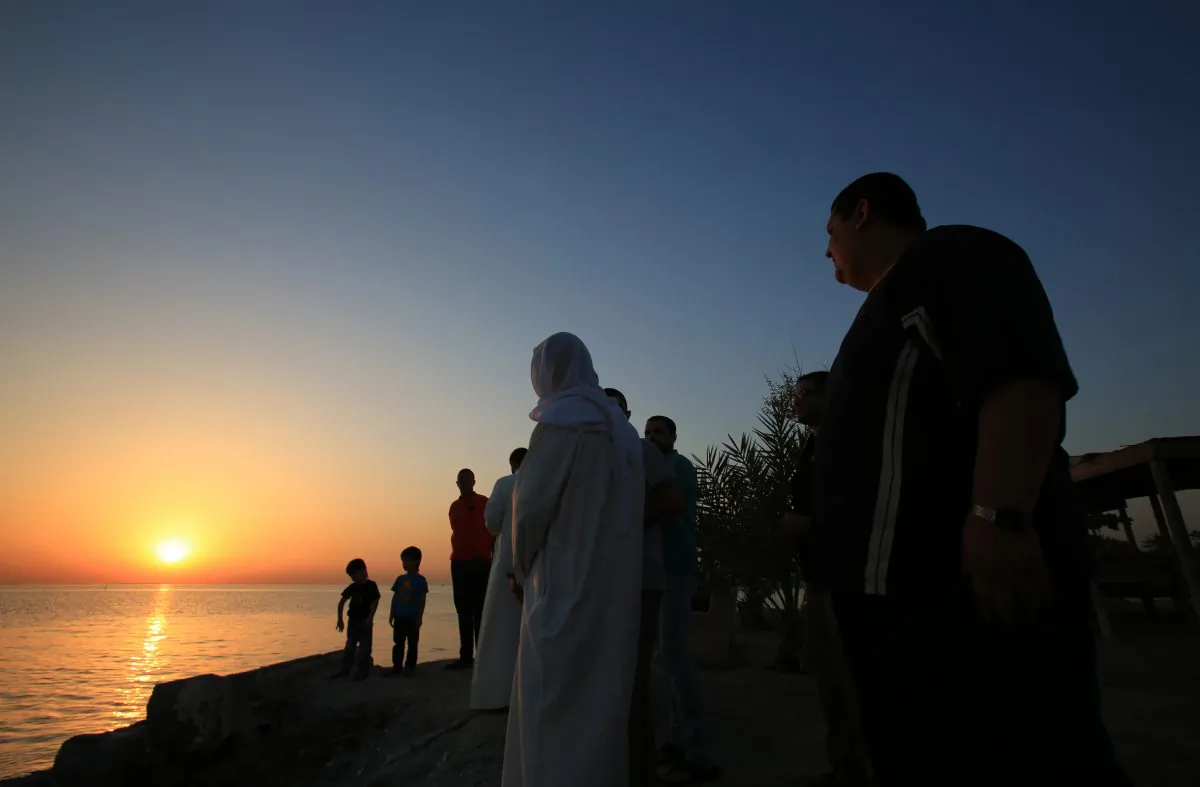 Bahrainis look for the sliver of a new moon that would indicate the start of the Islamic holy month of Ramadan, while standing on the shore of the Persian Gulf in the western village of Karzakan, Bahrain, Saturday, June 28, 2014. Ramadan, for observant Muslims, is a time of fasting, prayer and charitable giving. Bahraini officials announced Ramadan would begin Sunday. (AP Photo/Hasan Jamali)