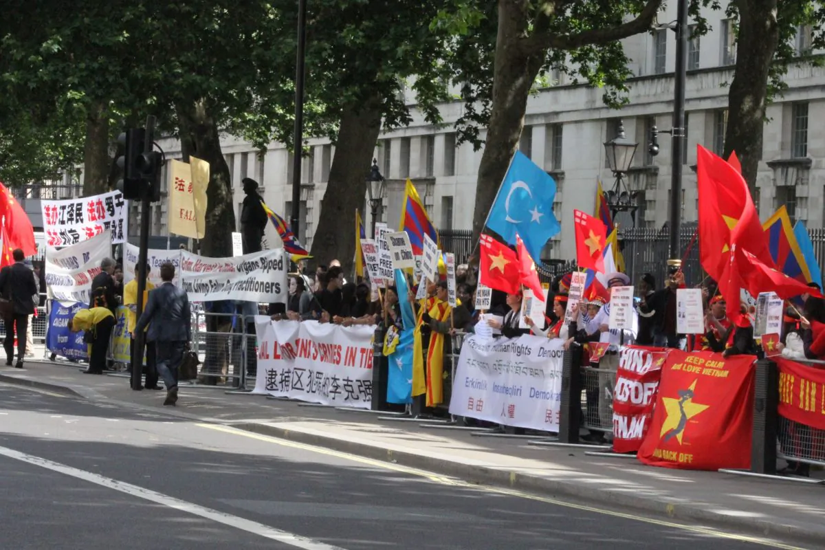 The Chinese Communist Party flag; Falun Gong banners; the red, blue and yellow flag of Tibet; the pale blue  flag of Uighuristan (Islamic Republic of East Turkestan); and the red Vietnamese flag with Flag of St George in the top corner to represent English Vietnamese; at Whitehall on June 17. (Wenjing/Da Ji Yuan)