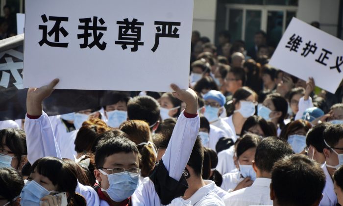 Hospital workers hold banners as they protest against attacks on medical workers outside the No. 1 People's Hospital in Wenling, east China's Zhejiang province, on Oct. 28, 2013. The relationship between patients and hospitals has often been characterized by mistrust, and sometimes outright violence. (Jin Yunguo/AFP/Getty Images)