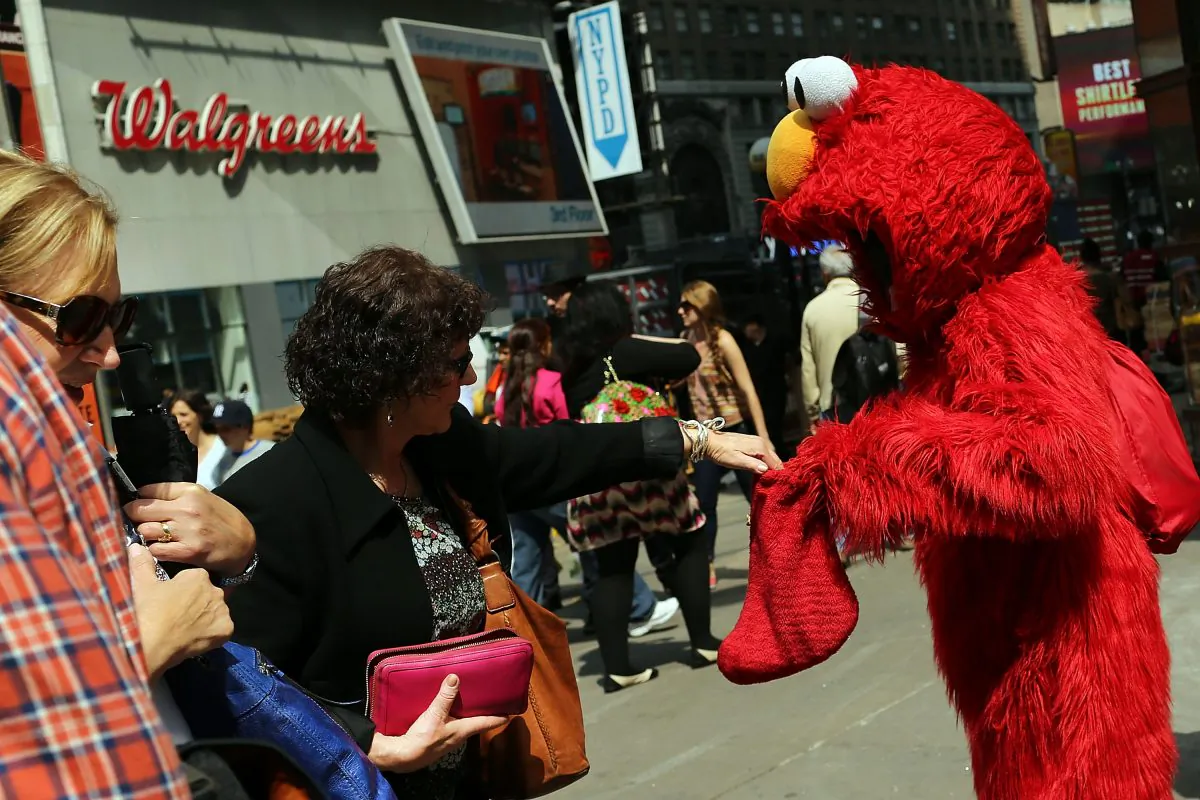 A tip is given to a man dressed as the Elmo children's television character after he posed for photos in Times Square, New York City, April 10, 2013. (Spencer Platt/Getty Images)