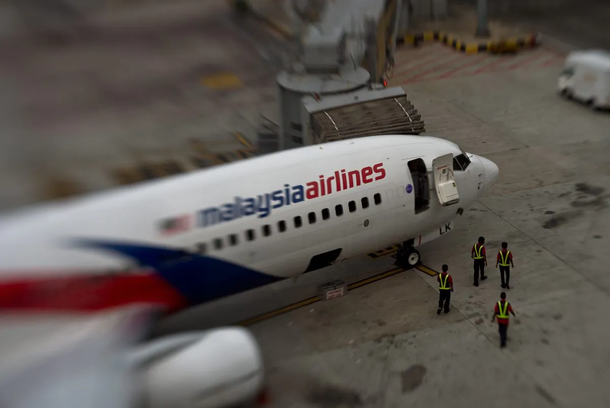 In this picture taken with a Tilt and shift lens, groundstaff walk past a Malaysia Airlines plane parked on the tarmac at the Kuala Lumpur International Airport in Sepang. (Manan Vatsyanyana/AFP/Getty Images)