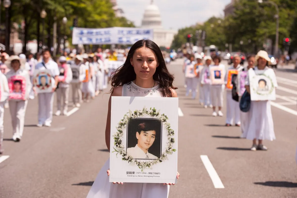 A young women holds a portrait of Falun Gong practitioner who was killed in the persecution in China, during a parade in Washington, on July 17, 2014. (Dai Bing/Epoch Times)
