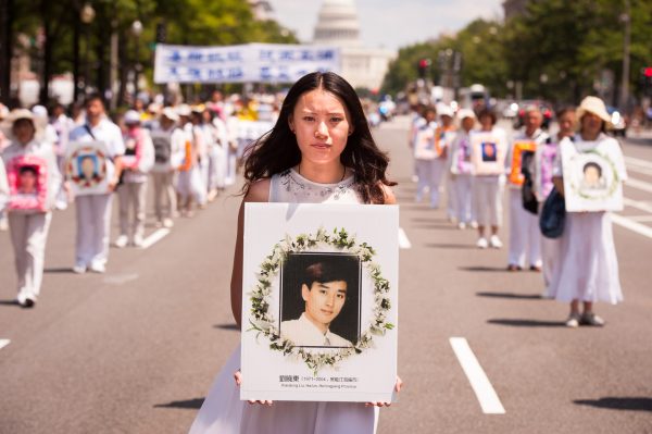 A women holds a photo of a fellow Falun Gong practitioner killed for his beliefs, during a parade calling for an end to the persecution in China, in Washington, D.C., on July 17, 2014. Today marks the 15th year of the persecution that began on July 20, 1999, in China. (Edward Dai/Epoch Times)