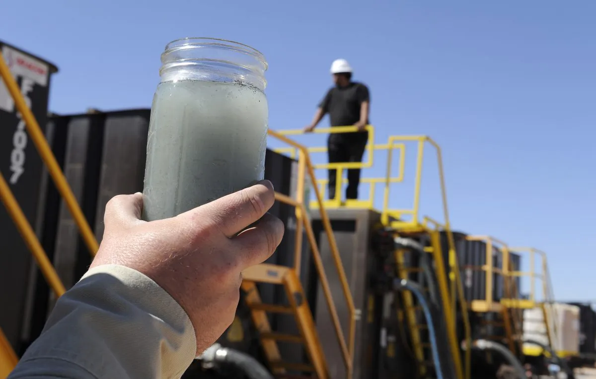 A jar holding waste water from hydraulic fracturing is held up to the light at a recycling site in Midland, Texas, Sept. 24, 2013. The drilling method known as fracking uses huge amounts of high-pressure, chemical-laced water to free oil and natural gas trapped deep in underground rocks. With fresh water not as plentiful companies have been looking for ways to recycle their waste. (AP Photo/Pat Sullivan)