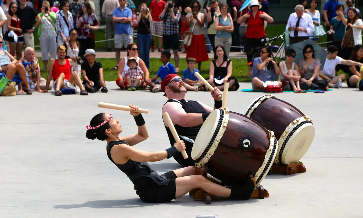 Two members of Oto-Wa Taiko play while sitting on the ground at the Japanese Summer Festival in Ottawa on July 19, 2014. (Pam McLennan/Epoch Times)