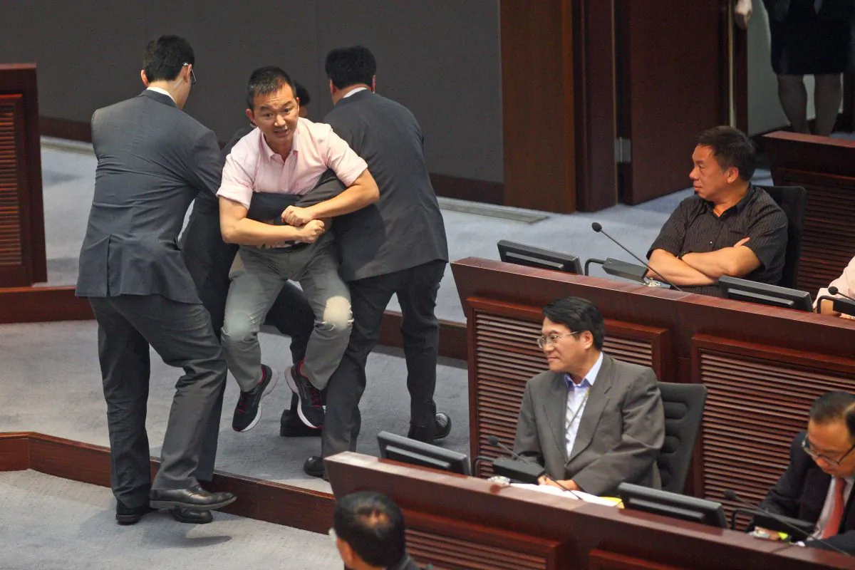 LegCo member Raymond Chan Chi-chuen is carried out by security guards after protesting the government reports that he feels do not honestly reflect Hong Kong citizens’ demand for civic nomination on July 15, 2014. (Epoch Times)