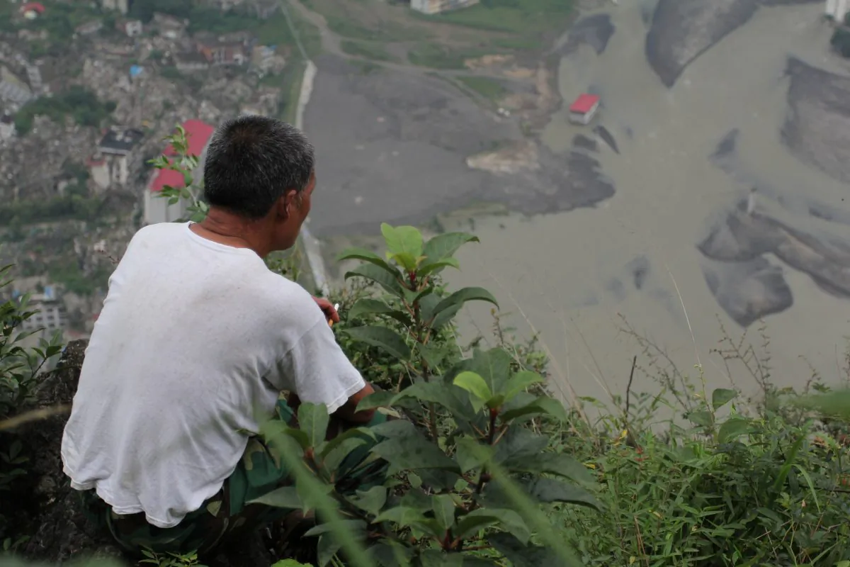 Li Mingshan, looking down at the old city, on the mountaintop after the 2008 Sichuan earthquake that decimated the community of Beichuan. (Shaoguang Sun)
