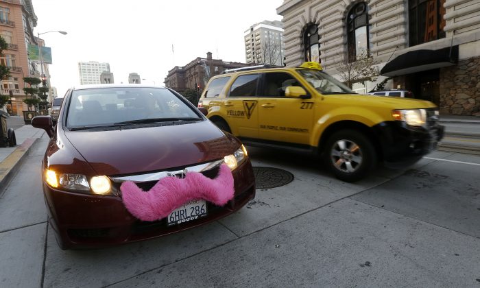 Lyft driver Nancy Tcheou waits in her car after dropping off a passenger as a taxi cab passes her in San Francisco, Jan. 4, 2013. Uber and Lyft have been getting bashed by New York City's taxi and livery industry in recent weeks. (AP Photo/Jeff Chiu)