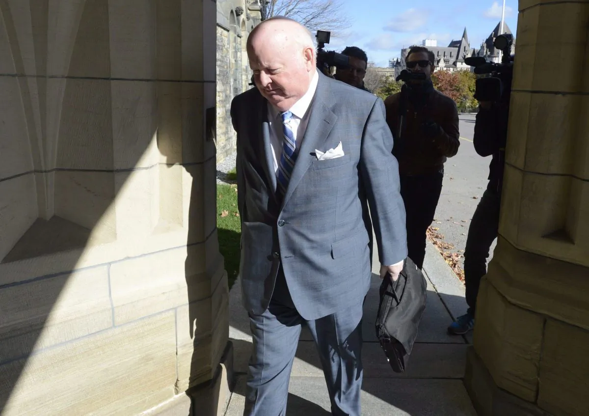 Sen. Mike Duffy walks to the Senate on Parliament Hill on Oct. 28, 2013. Now that Duffy has been formally charged, the Liberals are urging the ethics commissioner to re-open her investigation into the Senate expense scandal. (The Canadian Press/Adrian Wyld)