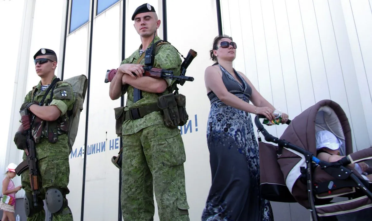 A woman pushes a baby in a stroller as she passes Ukrainian marines patrolling the Black Sea port of Odessa during Ukraine's Navy Day on July 27, 2014. (Alexey Kravtsov/AFP/Getty Images)