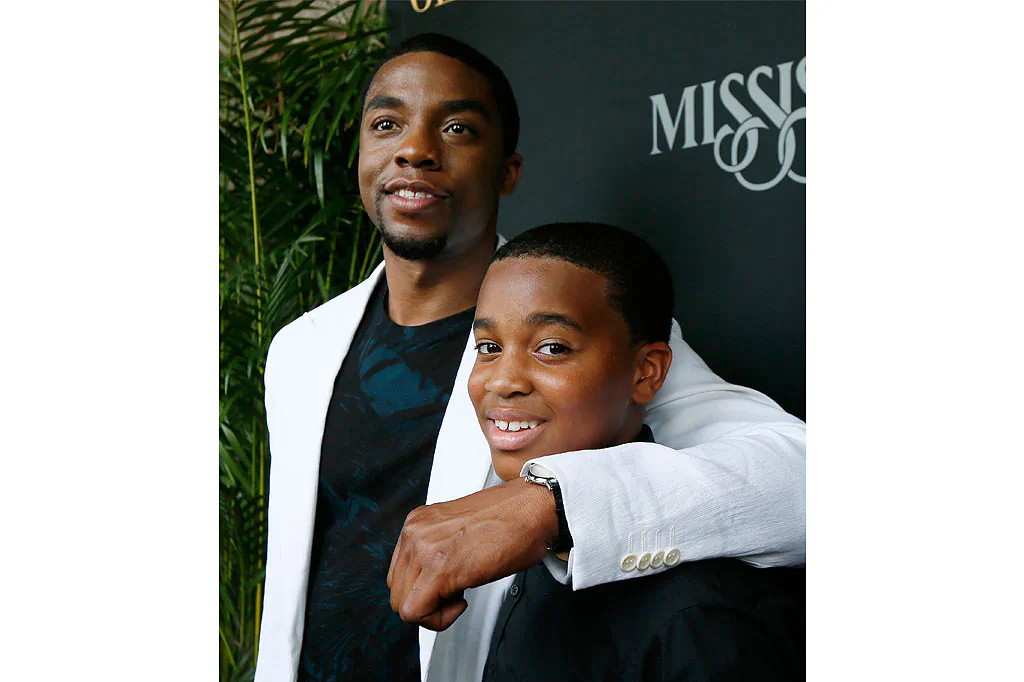 Chadwick Boseman, who stars as James Brown in "Get On Up," a movie based on the life story of "the Godfather of Soul," hugs Alvin Edney, 14, who played Brown's son Teddy, prior to a screening of the film, July 27 in Madison, Miss. (AP Photo/Rogelio V. Solis)