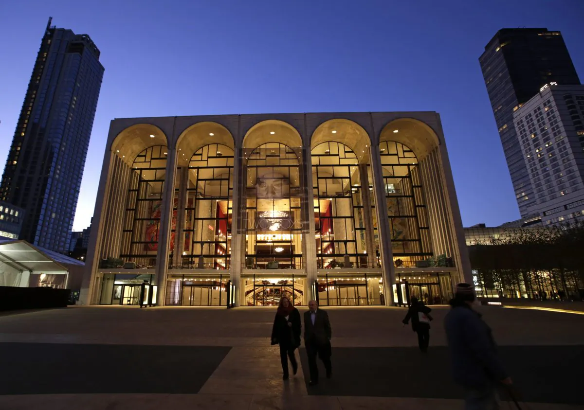 Pedestrians stroll at dusk in front of the Metropolitan Opera House in New York's Lincoln Center, November 13, 2013. Fractious labor negotiations threaten to disrupt the Met's new season for the first time in more than 30 years. (AP Photo/Kathy Willens)
