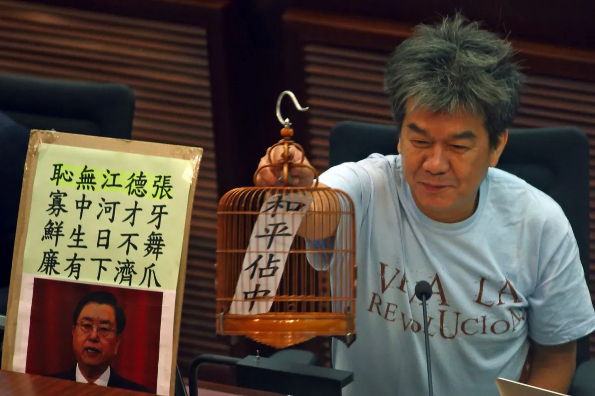 Legislative councilor Leung Kwok-hung puts out a birdcage prop to satirize the Chinese and Hong Kong governments’ giving Hong Kong people a “birdcage constitutional reform,” in the LegCo chamber on July 21. (Epoch Times)