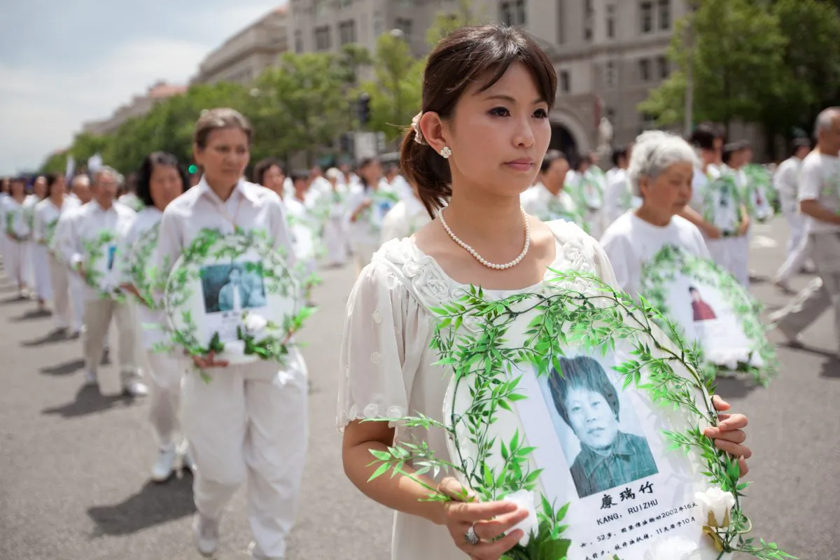 Marching Falun Gong practitioners hold photos of victims of the persecution during a parade in Washington, D.C., on July 18, 2011. (Epoch Times)