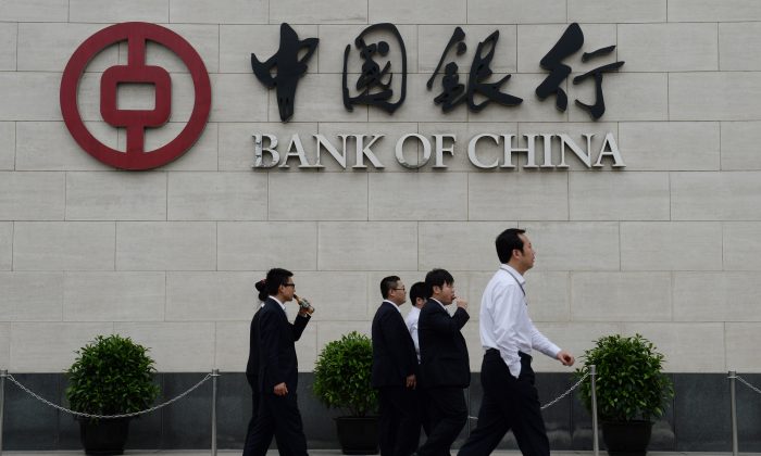 Bank workers walk outside the headquarters of the Bank of China in the Xidan District of Beijing on May 8, 2013. The state-owned Bank of China was accused of money laundering by Party mouthpiece Chinese Central Television on July 9. (Mark Ralston/AFP/Getty Images) 