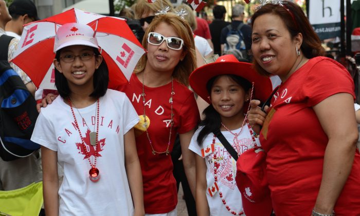 A family decked out in Canada Day attire stops to pose for a picture, July 1, 2014, in Ottawa. (Chrisy Trudeau/Epoch Times)