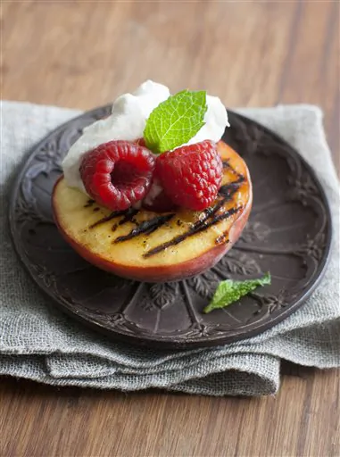 This grilled peaches, berries, and cream dessert is simple to make and takes just minutes to cook and assemble. (AP Photo/Matthew Mead) 