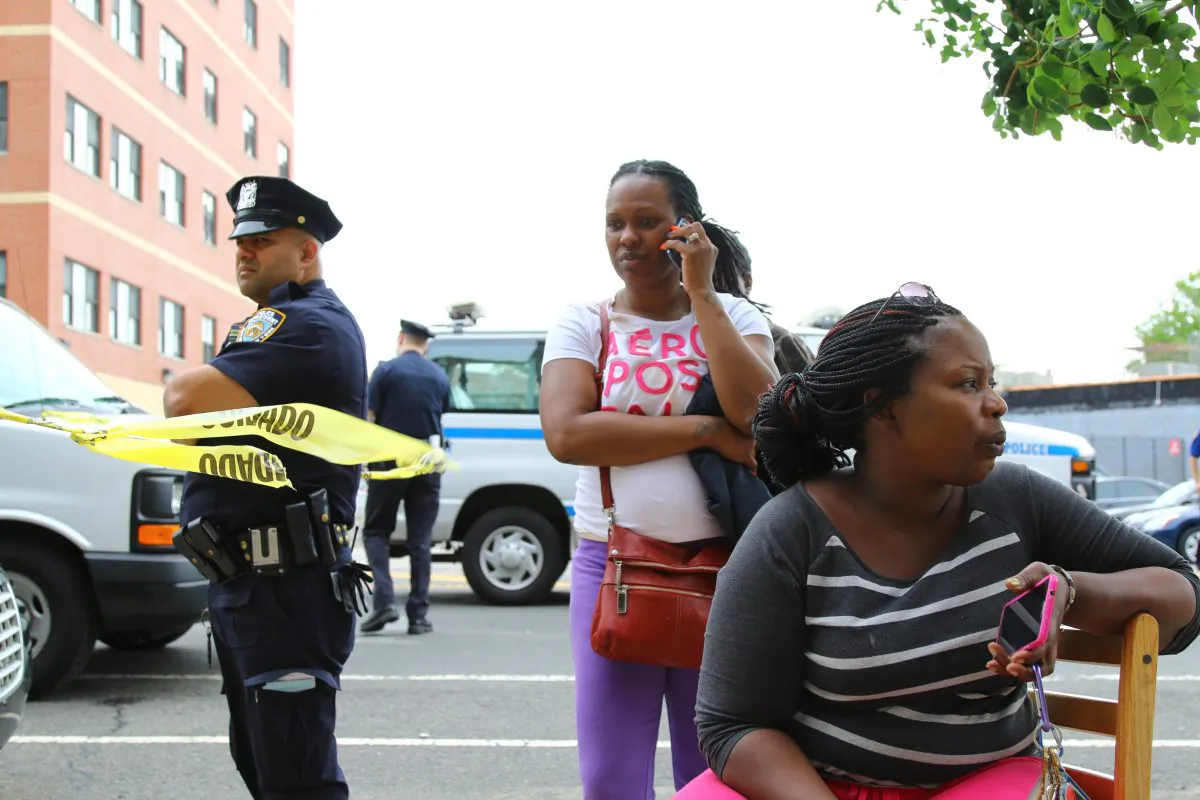 Leslie-Ann Robert Smith (R) sits outside of her Rockaway Parkway apartment building after lightning set it on fire overnight in Brownsville, Brooklyn, on July 4, 2014. (Brendon Fallon/Epoch Times) 
