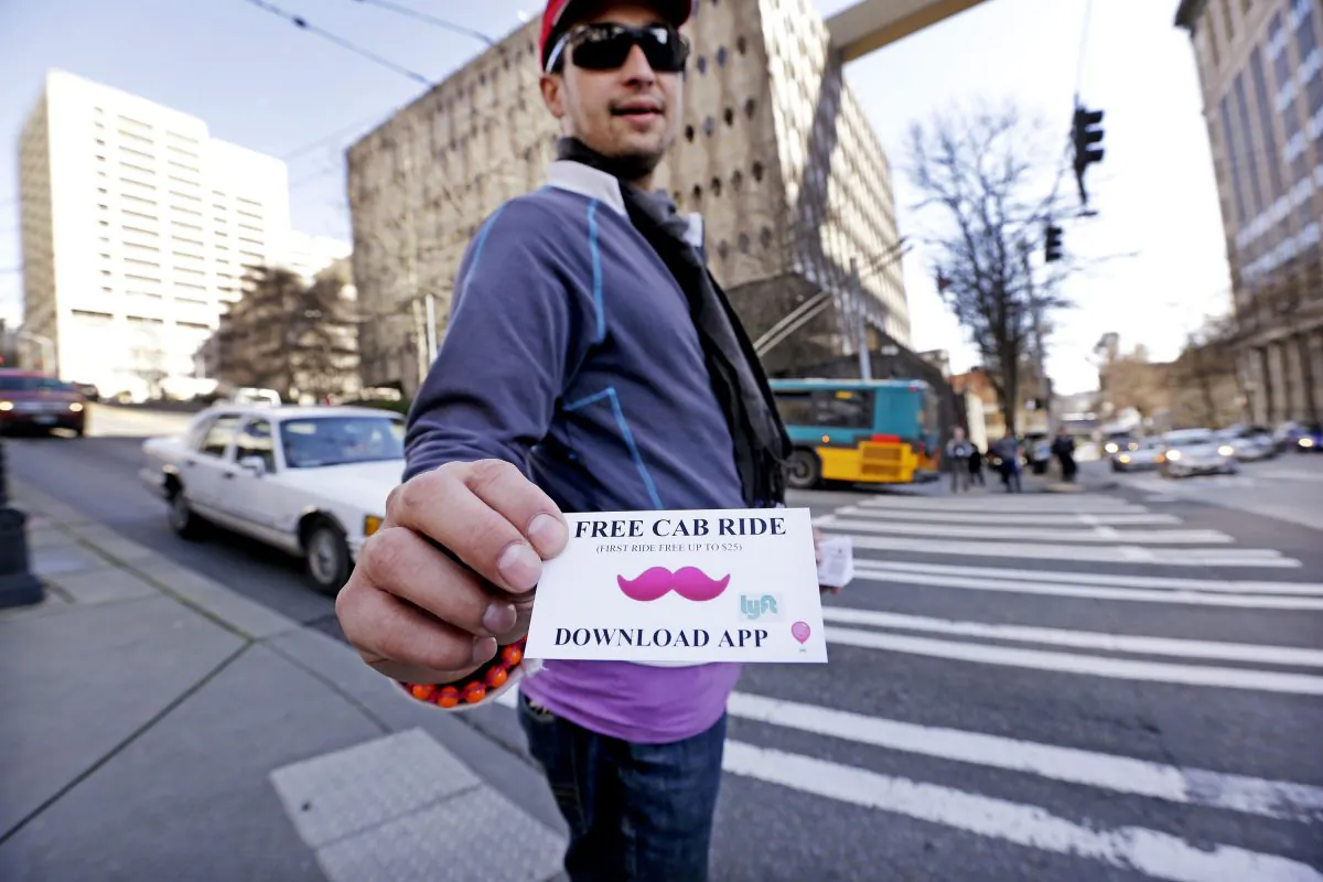 Jerad Bernard hands out cards to passers-by offering one free ride through the Lyft ridesharing service in Seattle, March 14. Beginning at 7 p.m. on Friday, residents in Brooklyn and Queens, N.Y. can hail a car from Lyft’s 500-unit fleet on their smartphones. (AP Photo/Elaine Thompson)