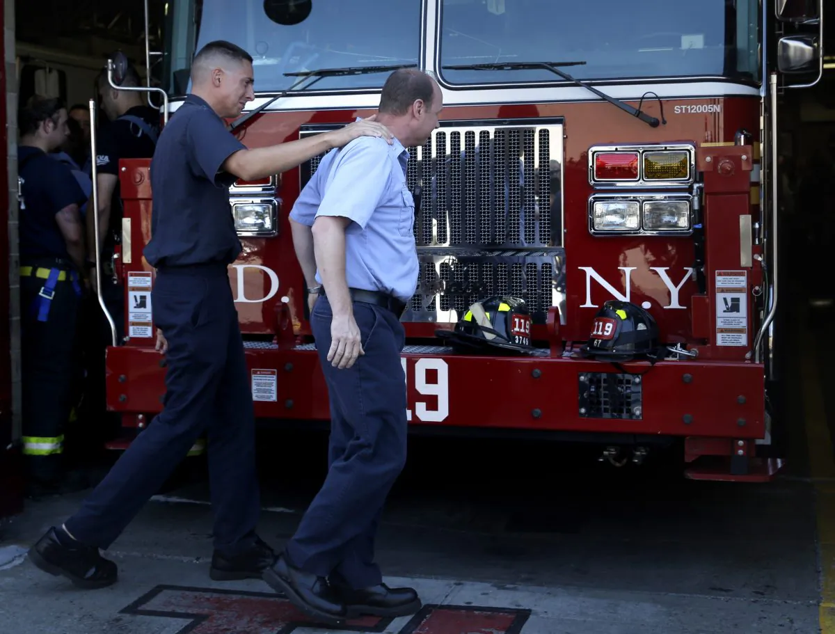 Firefighters comfort one another after bunting was hung in honor of Lt. Gordon Ambelas in New York, Sunday, July 6, 2014. The Fire Department of New York is mourning the death of Ambelas, who became trapped while looking for victims in a public-housing high-rise blaze, the first to die in the line of duty in more than two years. Ambelas died Saturday after suffering multiple injuries while on the 19th floor of the 21-story building in the Williamsburg section of Brooklyn, officials said. (AP Photo/Seth Wenig)