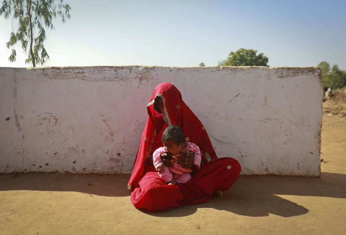 Krishna, 14, sits with her four-month-old baby outside her house in a village in the northwestern state of Rajasthan, India, Jan. 21, 2013. Krishna was married to her husband Gopal when she was 11 and he was 13. Canada is contributing $20 million over two years to UNICEF toward ending child marriage in six countries. (REUTERS/Danish Siddiqui)