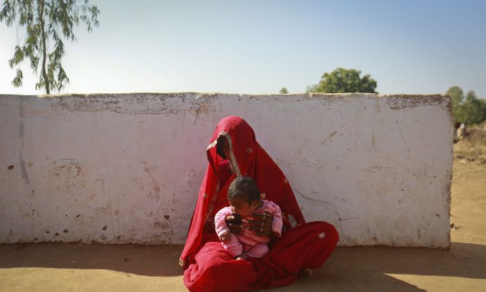 Krishna, 14, sits with her four-month-old baby outside her house in a village in the northwestern state of Rajasthan, India, Jan. 21, 2013. Krishna was married to her husband Gopal when she was 11 and he was 13. Canada is contributing $20 million over two years to UNICEF toward ending child marriage in six countries. (REUTERS/Danish Siddiqui)