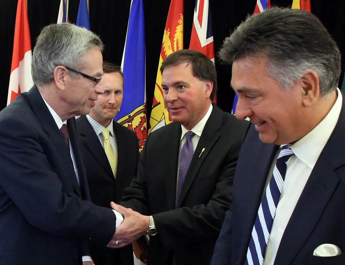 Finance Minister Joe Oliver shakes hands with Saskatchewan Justice Minister Gordon Wyant as New Brunswick Justice Minister Troy Lifford (centre left) and Ontario Finance Minister Charles Sousa look on at a news conference after signing an agreement to move towards a cooperative capital markets regulatory system in Ottawa, July 9, 2014. (The Canadian Press/Fred Chartrand)