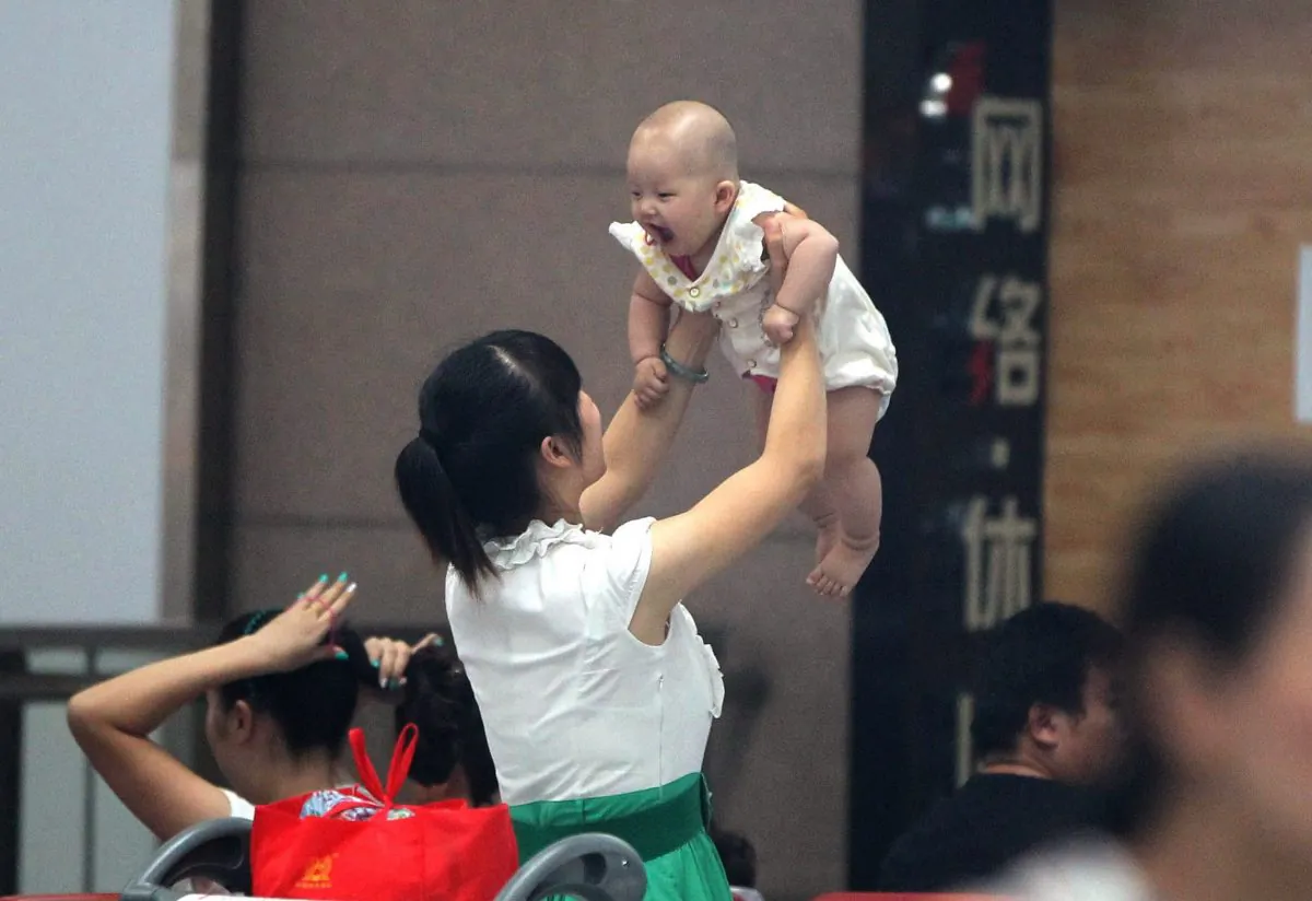 A woman holds her baby in Zhengzhou, in central China's Henan Province on July 29, 2014. Recent reports in China's state-run media have told of the excessive profits, exploitation of surrogate mothers, and sex-selective abortions that accompany the business of surrogacy. (STR/AFP/Getty Images)