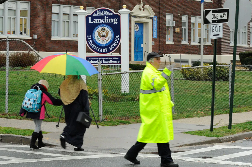 A student and her mother pass a crossing guard as they arrive at Landing Elementary School in Glen Cove, N.Y., Friday, April 12, 2013. A new law is raising the penalty for assaulting crossing guards doing their jobs. (AP Photo/Kathleen Malone-Van Dyke)