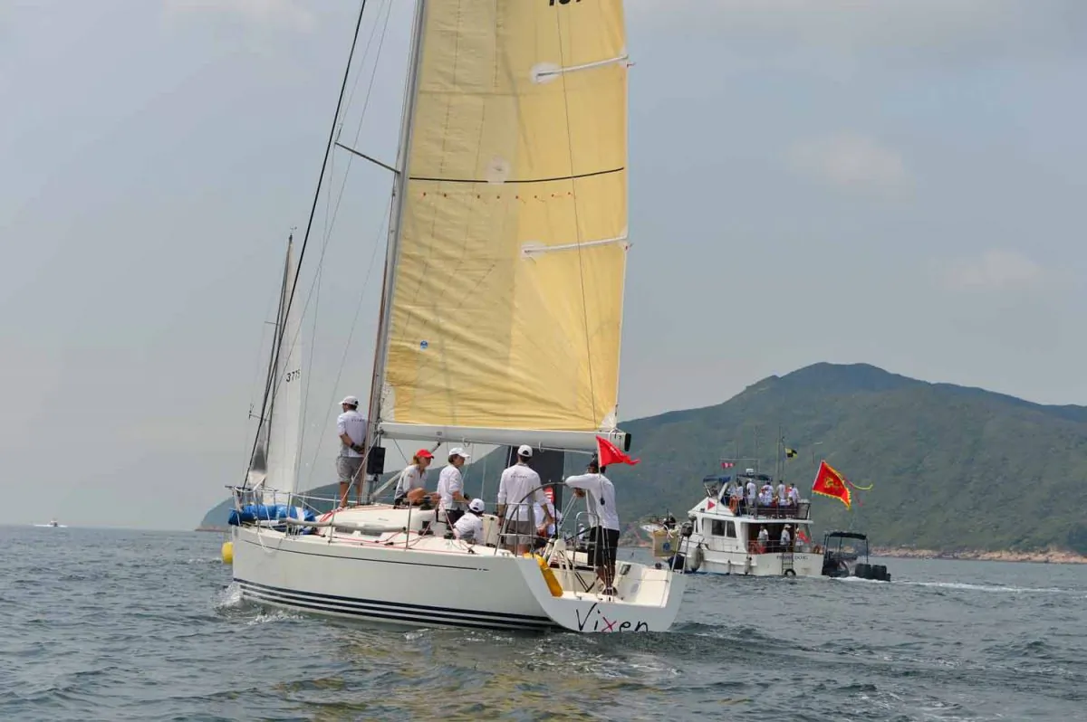The sombre crew of “Vixen” mourning the loss of their leader Peter McCaffery before the start of the Mirs Bay Passage Race on Saturday Aug 2 2014, In the background, flying the Club’s flag at half mast is the Hebe Haven Committee boat with members of the McCaffery family and friends on board. (Bill Cox/Epoch Times)