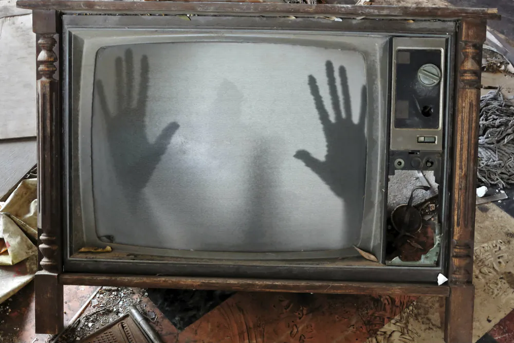 A concept image of a ghost appearing on a flickering television set. Could the dead communicate through electronics as some have claimed? Dr. Imants Barušs investigates. (Thinkstock)