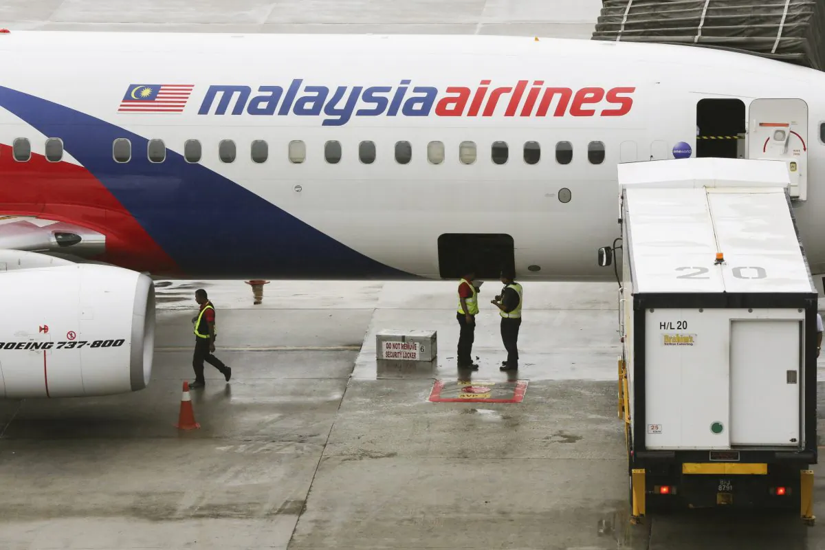 Ground crew stand near a Malaysia Airlines aircraft on the tarmac at the Kuala Lumpur International Airport (KLIA) in Sepang, Malaysia, Tuesday, May 27, 2014. A group of researchers used confirmed debris locations of flight MH370 to predict the missing plane's most likely location in a study published in an open access journal on July 27. (AP Photo/Vincent Thian)