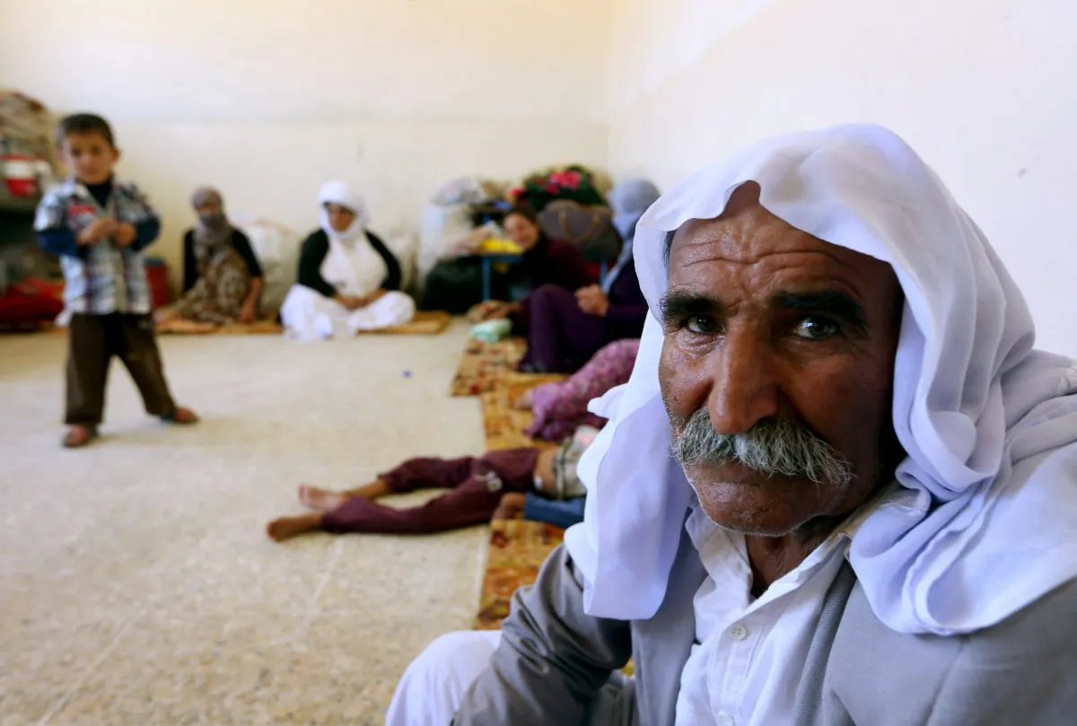 An Iraqi Yazidi family that fled the violence in the northern Iraqi town of Sinjar, sit at at a school where they are taking shelter in the Kurdish city of Dohuk in Iraq's autonomous Kurdistan region, on Aug. 5, 2014. Islamic State (IS) Sunni jihadists ousted the Peshmerga troops of Iraq's Kurdish government from the northern Iraqi town of Sinjar, forcing thousands of people from their homes. The Yazidis, are a small community that follows a 4,000-year-old faith and have been repeatedly targeted by jihadists who call them 'devil-worshipers' because of their unique beliefs and practices. (Safin Hamed/AFP/Getty Images)