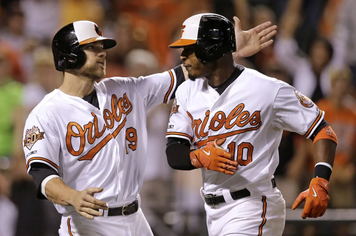 Baltimore Orioles' Chris Davis, left, greets teammate Adam Jones at home plate after he and Nick Markakis scored on Jones' home run in the eighth inning of a baseball game against the New York Yankees, Wednesday, Aug. 13, 2014, in Baltimore. (AP Photo/Patrick Semansky)