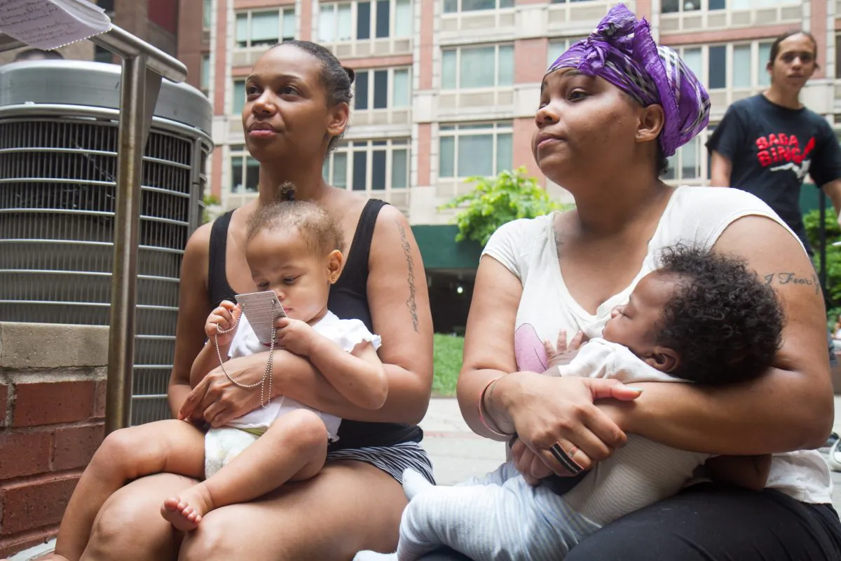 Tika Wilson (L) along with her friend who also lives in the homeless shelter at 4 E. 28th Street, wait outside in a plaza after a fire broke out in an apartment in the shelter, in Manhattan, on July 29, 2014. The building used to be the Hotel Latham which was later turned into a shelter. (Benjamin Chasteen/Epoch Times)