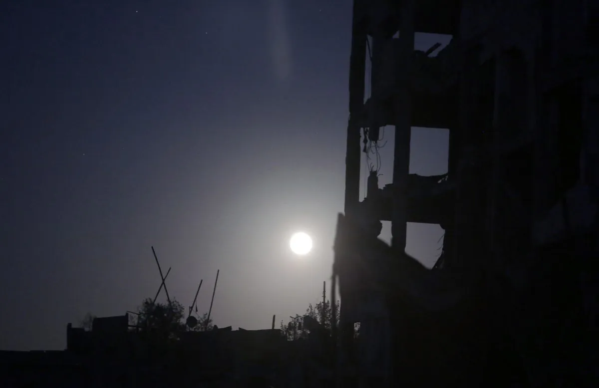 In this Aug. 11, 2014, photo a full moonshines on the destroyed al-Nada Towers residential neighborhood in the town of Beit Lahiya, northern Gaza Strip. Dozens of residents the al-Nada Towers took advantage of the latest truce to visit their homes, salvage what they can and exchange tips on how best to seek and secure compensation for their homes. (AP Photo/Khalil Hamra)