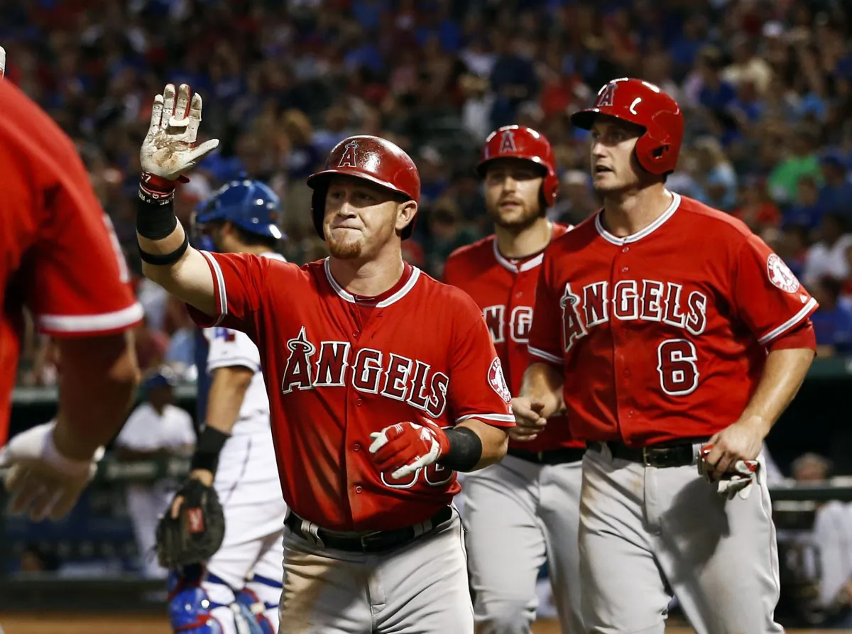 Los Angeles Angels' Kole Calhoun, left, is congratulated as he heads to the dugout after hitting a three-run home run scoring David Freese (6) and Chris Iannetta against the Texas Rangers during the fifth inning of a baseball game, Friday, Aug. 15, 2014, in Arlington, Texas. (AP Photo/Jim Cowsert)