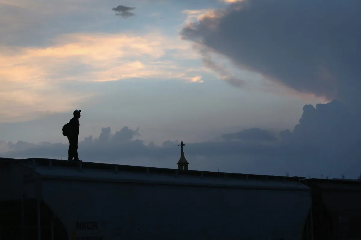 A Central American immigrant stands atop a freight train about to head north early in Arriaga, Mexico, 2013. (John Moore/Getty Images)