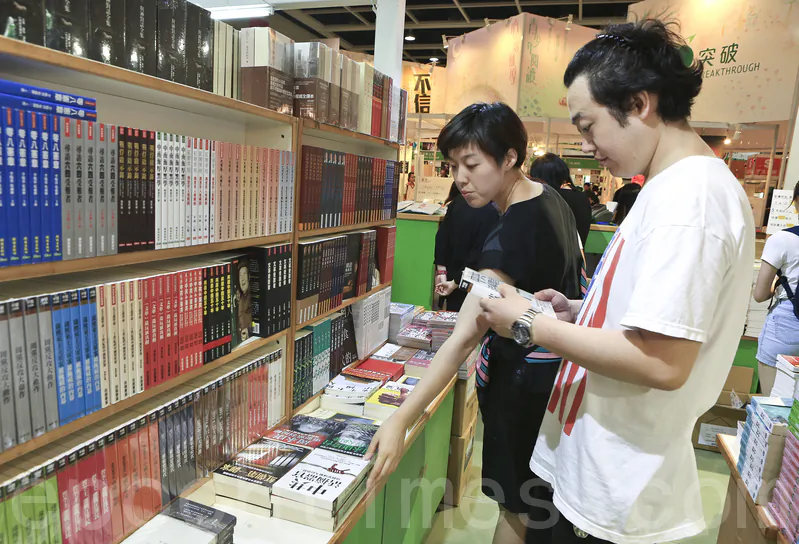 Mainland tourists check books in the section of books that are banned in mainland China. (Yu Gang/Epoch Times)