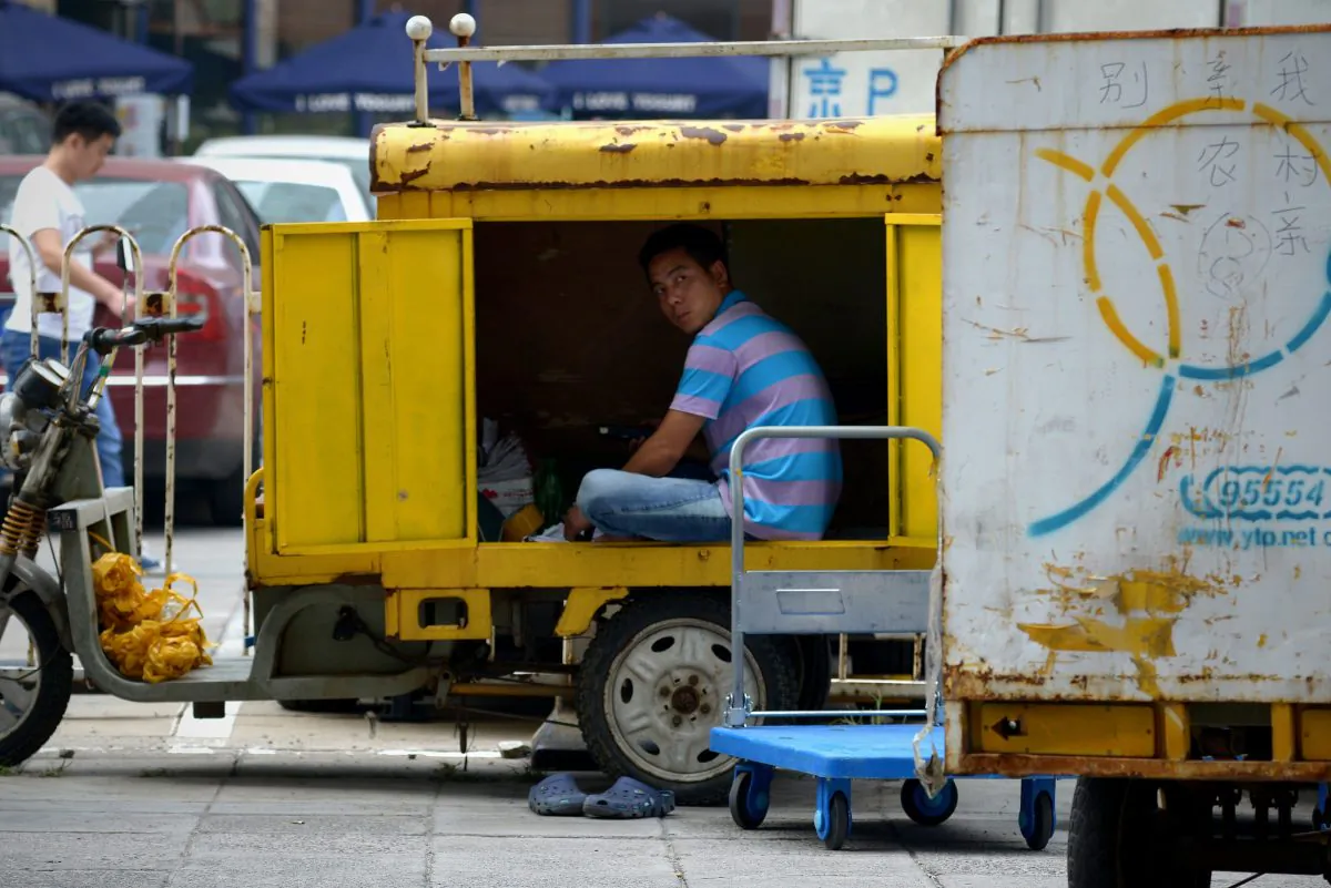 A delivery courier checks the packages inside his three-wheeled vehicle in Beijing on Aug. 18, 2014. Foreign direct investment into China dropped by more than a sixth year-on-year in July, the government said on Aug. 18. (Wang Zhao/AFP/Getty Images)