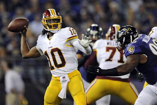 Washington Redskins quarterback Robert Griffin III, (10) throws to a receiver as he is pressured by Baltimore Ravens defensive tackle Brandon Williams in the first half of an NFL preseason football game, Saturday, Aug. 23, 2014, in Baltimore. (AP Photo/Gail Burton)