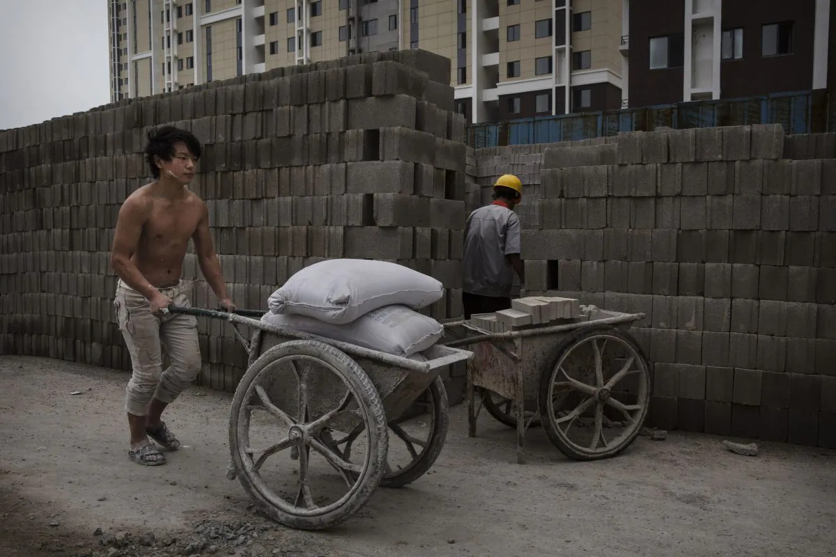 A Chinese construction worker pushes a load of concrete mix at the building site of a new apartment complex on Aug. 29, 2014 in Beijing, China. (Kevin Frayer/Getty Images)