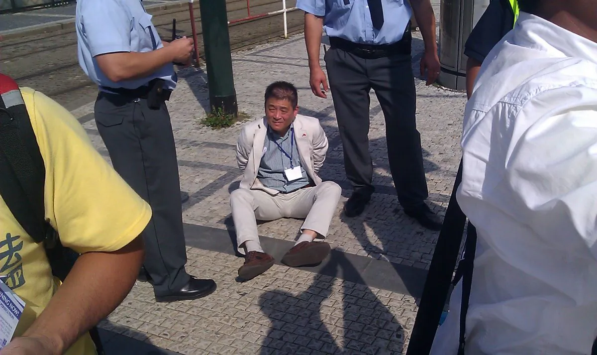 A staff member of the Chinese Embassy who attacked Falun Gong practitioners protesting outside the China Investment Forum has been handcuffed by Prague police, on Aug. 28, outside Prague Castle. (Sun Hao/Epoch Times)