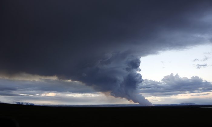 A plume of smoke rises from the lava eruption on Holuhraun, northwest of the Dyngjujoekull glacier in Iceland, Monday, Sept. 1, 2014.  Lava fountains danced along a lengthy volcanic fissure near Iceland's subglacial Bardarbunga volcano Sunday, prompting authorities to raise the aviation warning code to the highest level and close the surrounding airspace. The warning was lowered 12 hours later as visibility improved and it was clear that no volcanic ash was detected. (AP Photo/Eggert Johannesson)